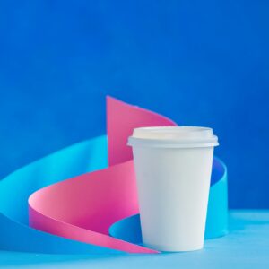 Blank paper cup for coffee on an abstract background with modern paper sculpture. Paper pyramids and